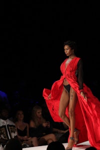 a woman in a red dress walking down the runway