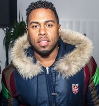a man in a fur jacket standing in front of a room