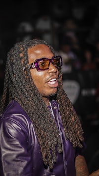 a man with dreadlocks wearing a purple jacket