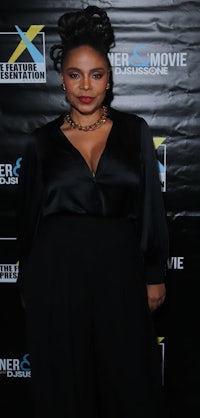 a woman in a black jumpsuit standing on the red carpet