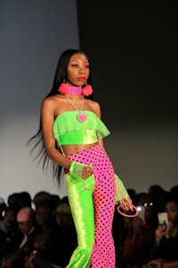 a woman wearing a green and pink outfit on the runway