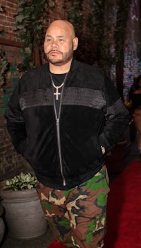 a bald man in camouflage pants standing on a red carpet