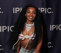 a woman in a bikini top and denim shorts posing for a photo